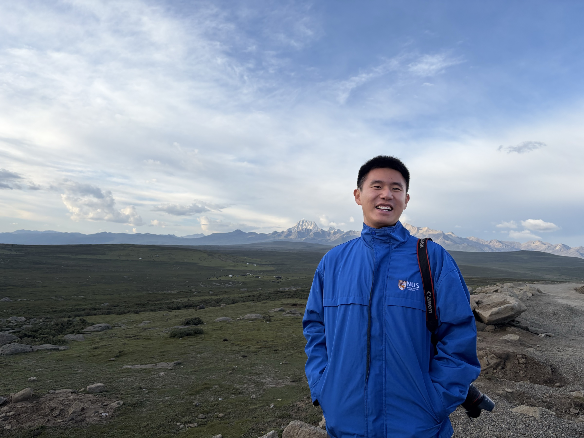 Zicheng Xie smiling in front of a mountain landscape